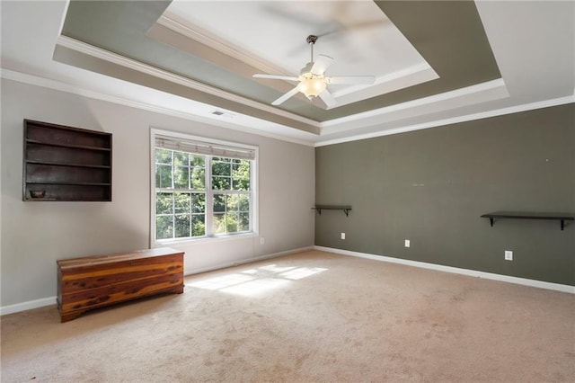 carpeted spare room featuring ceiling fan, a tray ceiling, and ornamental molding