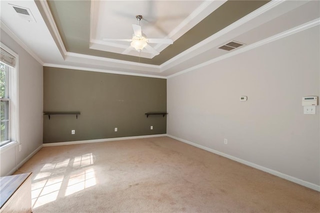 spare room featuring light carpet, ceiling fan, a raised ceiling, and crown molding