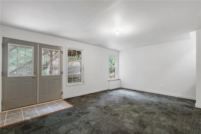 foyer entrance with dark colored carpet and a wealth of natural light