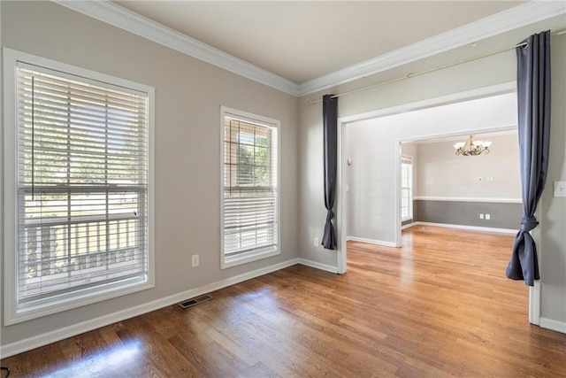 spare room with crown molding, a chandelier, and hardwood / wood-style flooring