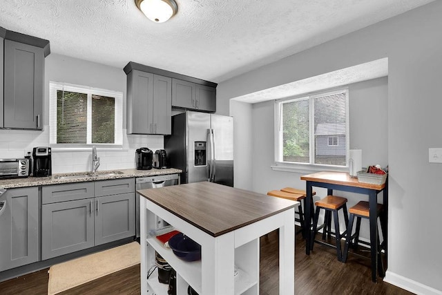 5461 Forest Path Ct, Stone Mountain, GA 30088 - kitchen with stainless steel appliances, a sink, gray cabinetry, open shelves, and a textured ceiling