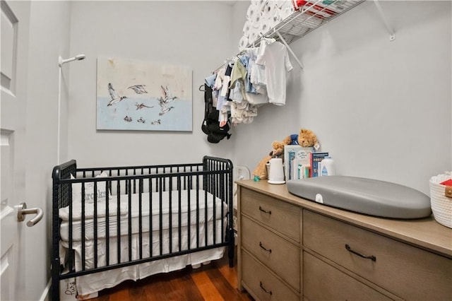 bedroom featuring dark wood-style floors and a crib