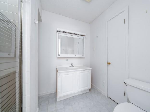 904 Bridge Ln SE, Smyrna, GA 30082 - bathroom with toilet, vanity, a shower with door, and baseboards