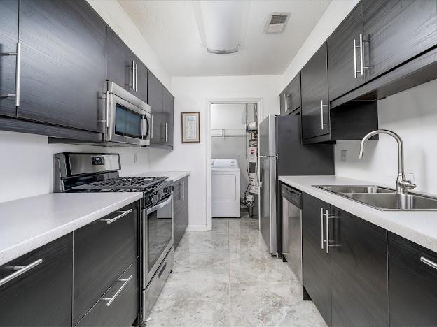 904 Bridge Ln SE, Smyrna, GA 30082 - kitchen with appliances with stainless steel finishes, a sink, dark cabinets, and light countertops
