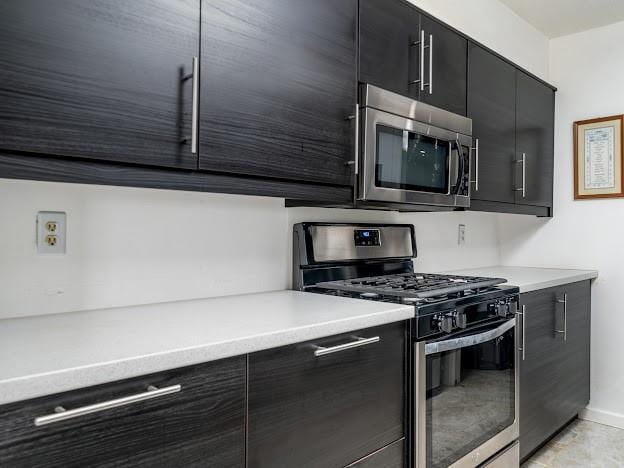 904 Bridge Ln SE, Smyrna, GA 30082 - kitchen with stainless steel appliances, dark cabinets, modern cabinets, light countertops, and baseboards