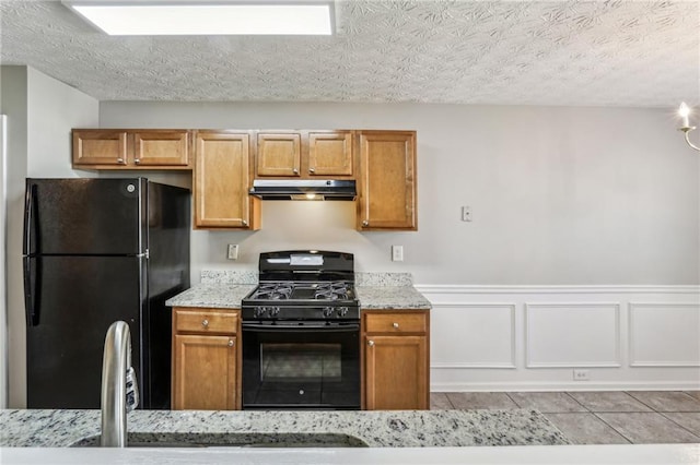 kitchen with light stone counters, light tile patterned floors, black appliances, and a textured ceiling