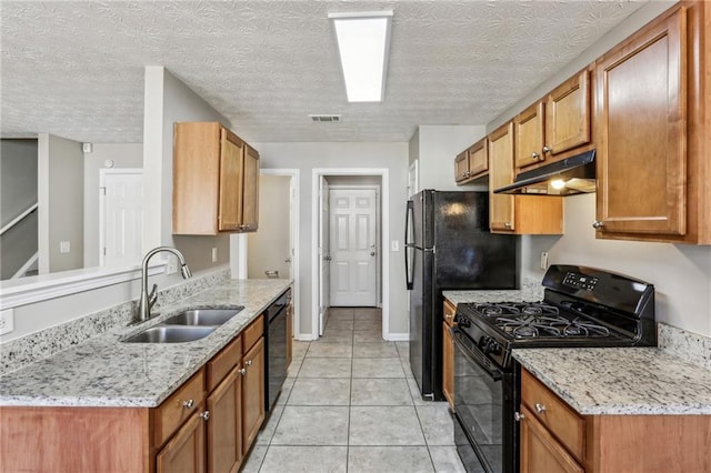 kitchen with sink, light tile patterned floors, black appliances, and light stone countertops