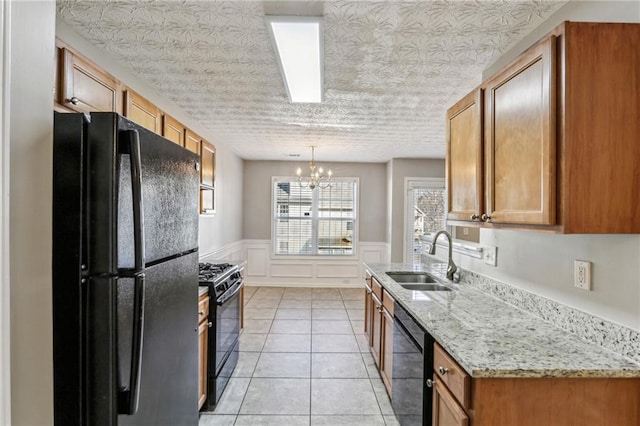 kitchen with sink, hanging light fixtures, light tile patterned floors, black appliances, and light stone countertops