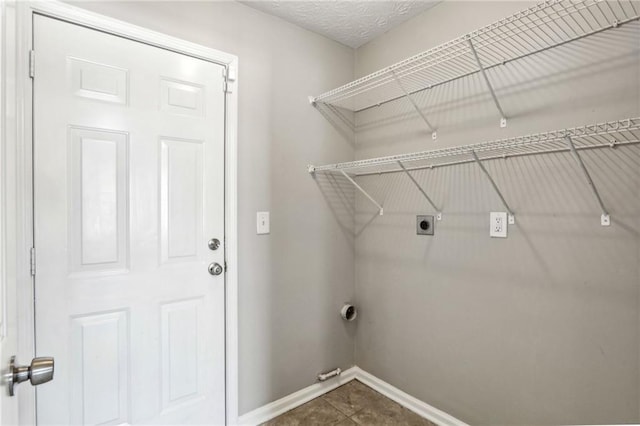 clothes washing area with electric dryer hookup and a textured ceiling