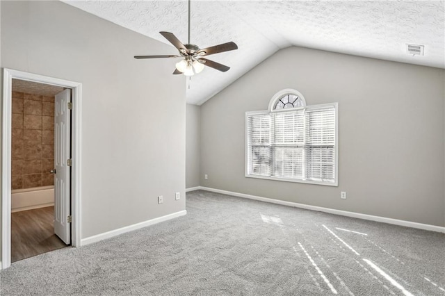 carpeted spare room with ceiling fan, lofted ceiling, and a textured ceiling