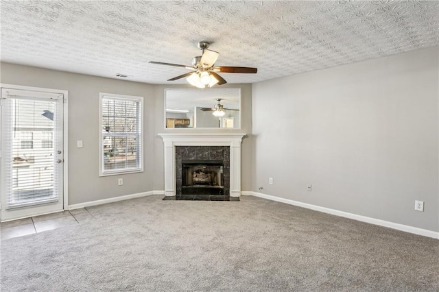 unfurnished living room featuring ceiling fan, a tile fireplace, a textured ceiling, and carpet flooring