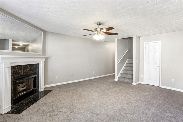 unfurnished living room with a premium fireplace, a textured ceiling, ceiling fan, and dark carpet