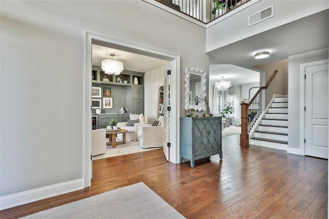 entryway with baseboards, visible vents, a chandelier, stairs, and hardwood / wood-style floors