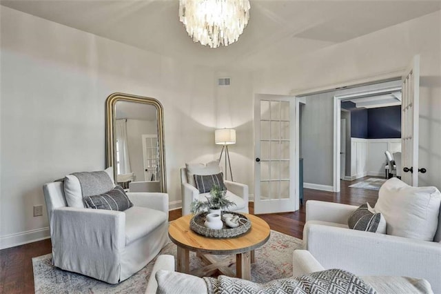 living area with wood finished floors, french doors, visible vents, and a notable chandelier