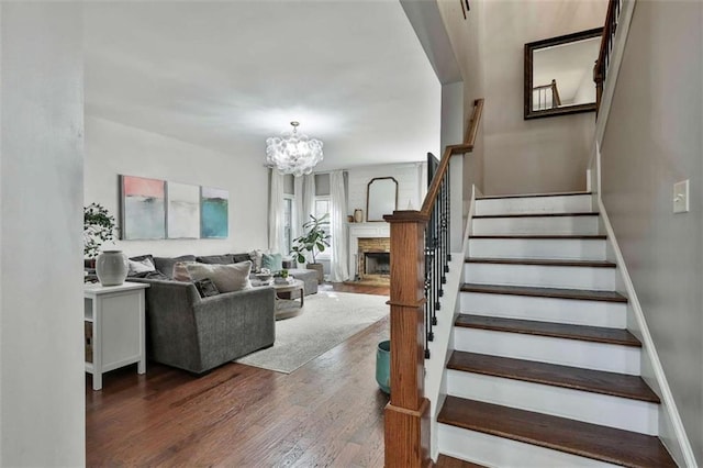 staircase featuring a chandelier, wood finished floors, and a fireplace