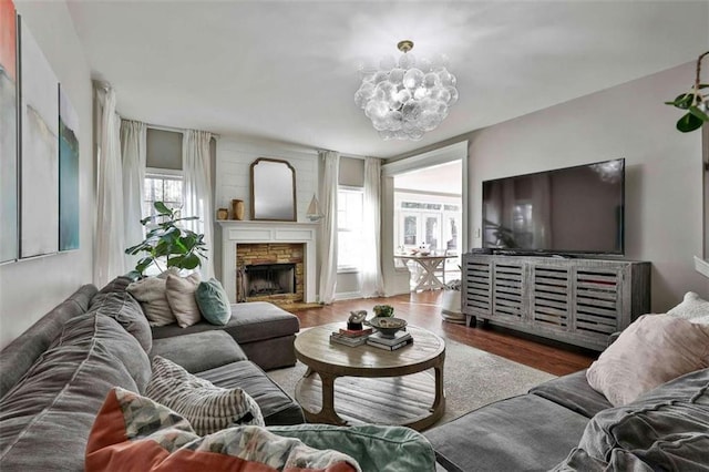 living area with wood finished floors, a fireplace, and a notable chandelier