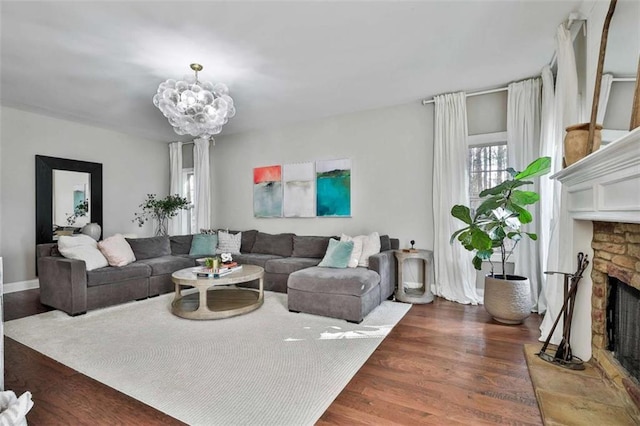 living area featuring an inviting chandelier, wood finished floors, and a fireplace