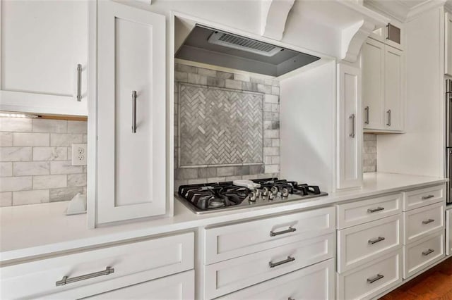 kitchen with decorative backsplash, light countertops, stainless steel gas stovetop, and exhaust hood