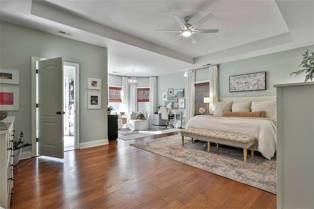 bedroom with baseboards, wood finished floors, and a tray ceiling