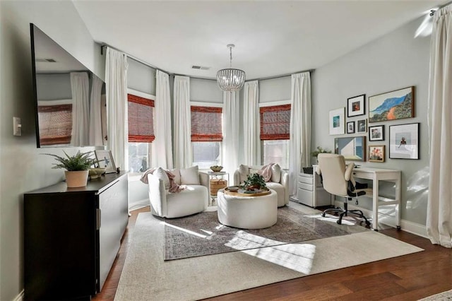 sitting room with a chandelier, plenty of natural light, visible vents, and wood finished floors