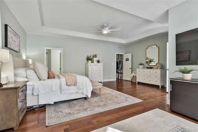 bedroom featuring ceiling fan, baseboards, dark wood-style floors, and a raised ceiling