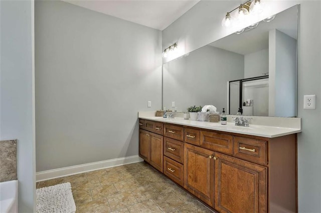 full bath with baseboards, a sink, double vanity, and a bathing tub