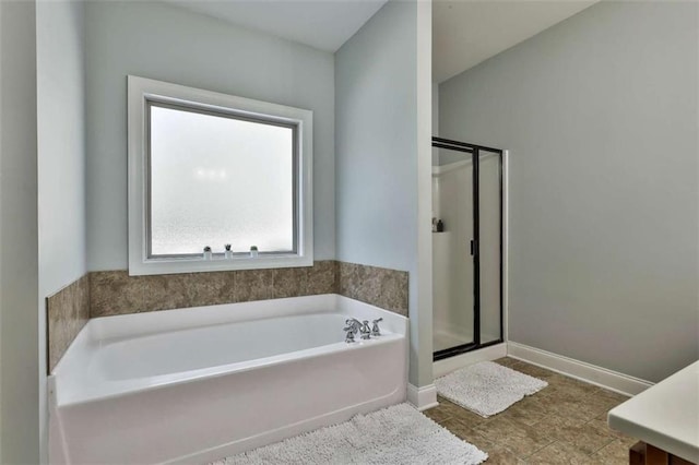 full bath featuring a bath, a shower stall, and baseboards