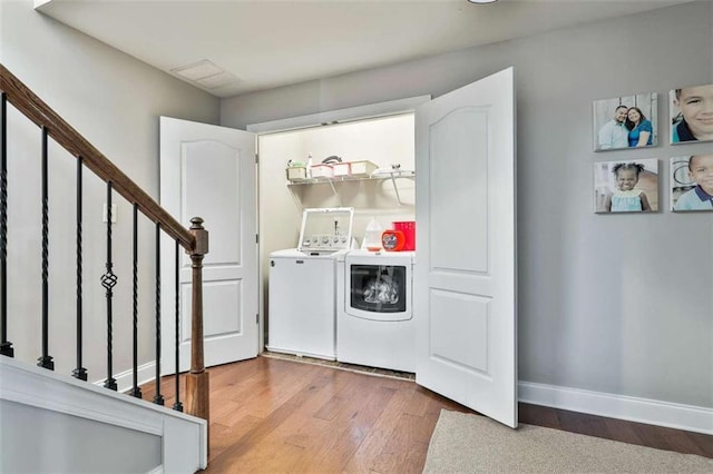 laundry room featuring washing machine and clothes dryer, baseboards, wood finished floors, and laundry area