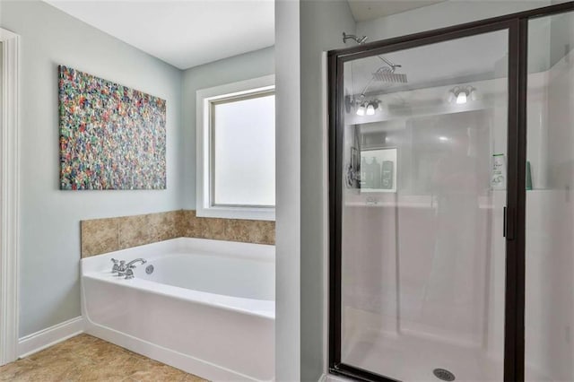 bathroom featuring a shower stall, a garden tub, and baseboards