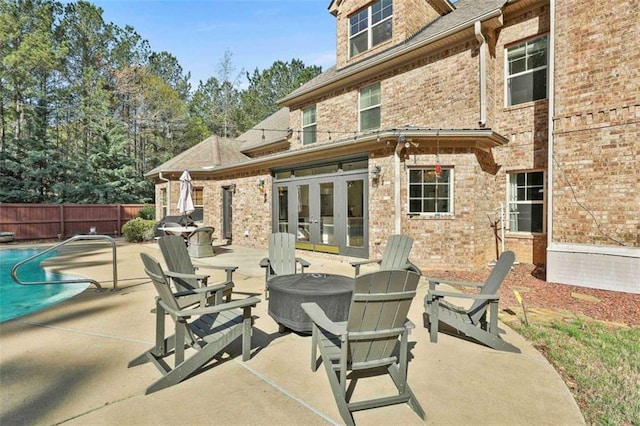 view of patio / terrace featuring a fire pit, french doors, a fenced in pool, and fence
