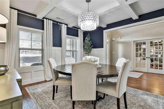 dining area with wood-type flooring, coffered ceiling, french doors, and a decorative wall