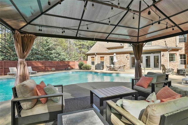 view of swimming pool featuring french doors, a fenced in pool, a fenced backyard, a gazebo, and outdoor lounge area