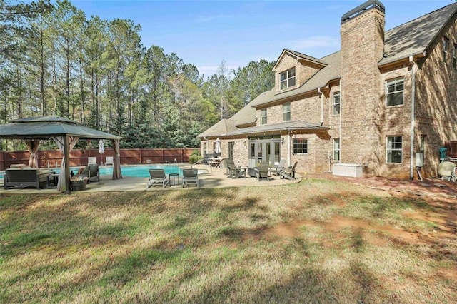 back of house with a gazebo, a chimney, a lawn, a fenced backyard, and a patio