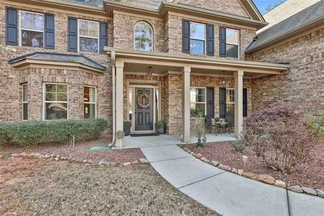 entrance to property featuring a porch and brick siding