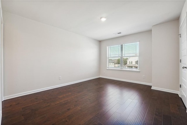 spare room with baseboards, dark wood finished floors, and visible vents