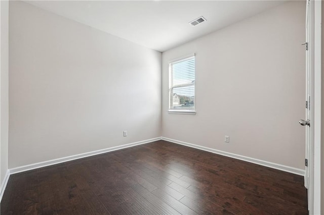 spare room with visible vents, baseboards, and dark wood-style floors