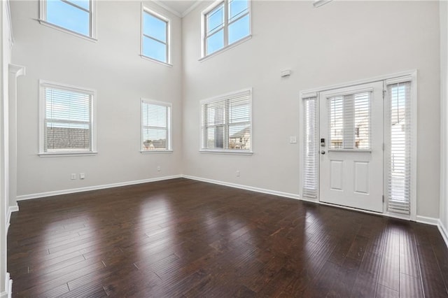 entrance foyer featuring baseboards, dark wood-style floors, and a towering ceiling