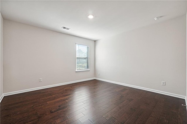 unfurnished room with baseboards, visible vents, and dark wood-style floors