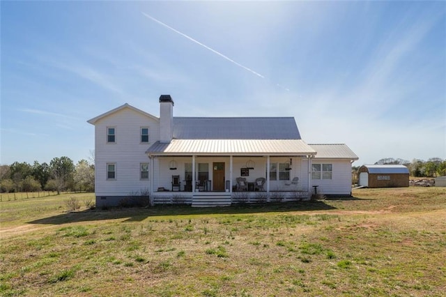 rear view of house with covered porch, a lawn, a chimney, metal roof, and crawl space