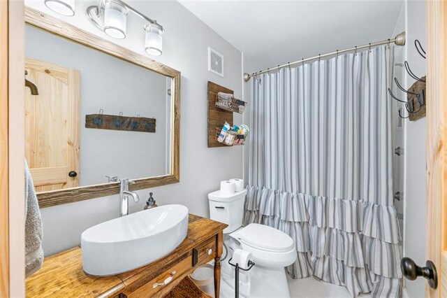 full bath featuring a shower with curtain, toilet, vanity, and visible vents