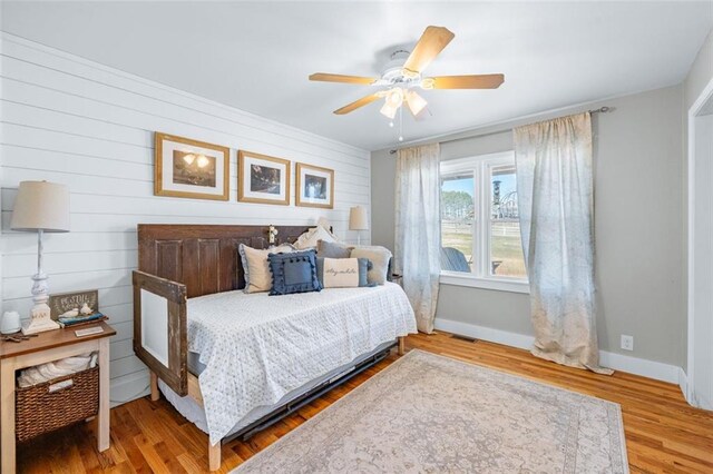 bedroom with ceiling fan, visible vents, baseboards, and wood finished floors