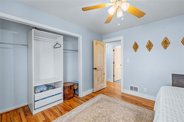 bedroom with a closet, visible vents, baseboards, and wood finished floors