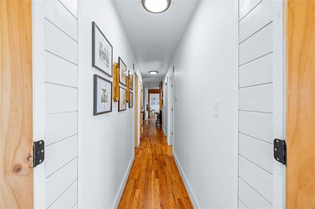 hall featuring light wood-type flooring and baseboards