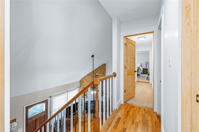 hallway featuring an upstairs landing and light wood-style floors