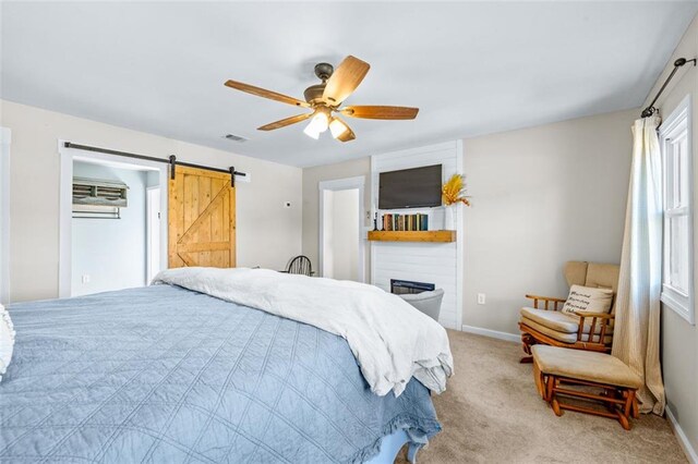 bedroom featuring visible vents, baseboards, a barn door, light carpet, and a ceiling fan