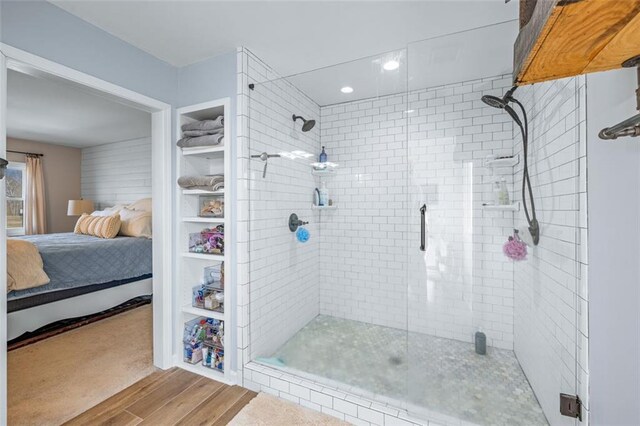 ensuite bathroom featuring connected bathroom, wood finished floors, and a stall shower