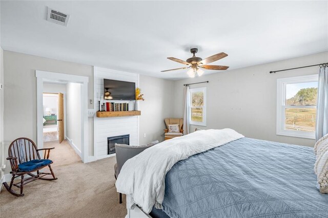 bedroom with visible vents, baseboards, light carpet, a fireplace, and a ceiling fan