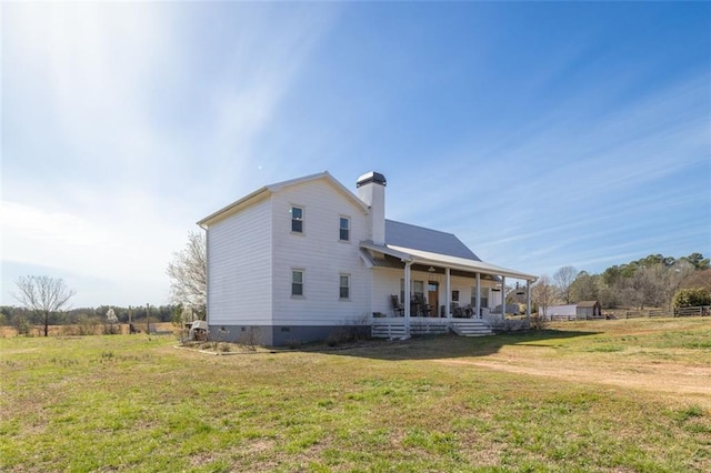 view of side of home featuring a porch, a yard, a chimney, and crawl space