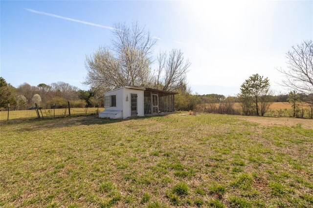 view of yard with a rural view, an outbuilding, and fence