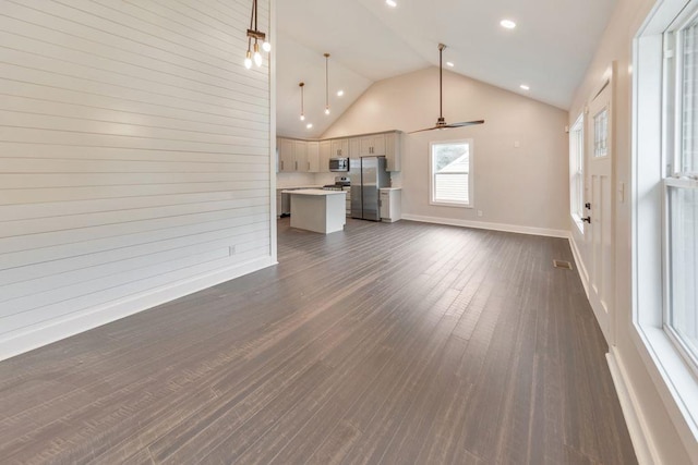 unfurnished living room with wooden walls, high vaulted ceiling, dark hardwood / wood-style floors, and ceiling fan